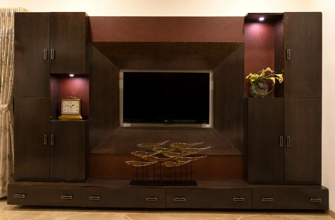A dark wooden wall unit with a flat-screen TV, a desk clock and lit shelves, where a XerquvaTV IPTV streaming box would sit