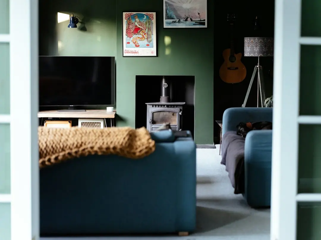 A living room with green walls, a wall-mounted TV and a blue armchair, set up for XerquvaTV premium IPTV